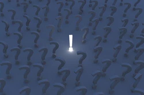 illuminated exclamation mark in a field of dark question marks