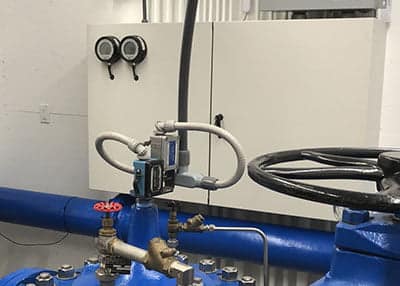 Two APG PG10 digital pressure gauges mounted on the door of a deep well control cabinet with remote heads on associated piping