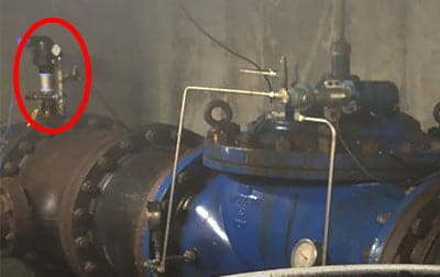A pressure transmitter and an old dial gauge on one side of an under-street pressure relief valve