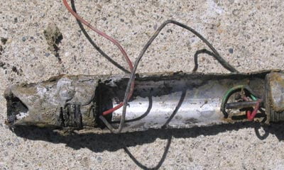 A dirty and broken metallic pressure sensor is shown with wires hanging out of it.