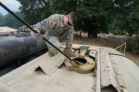 A national guard soldier checks fuel level manually with a dip stick