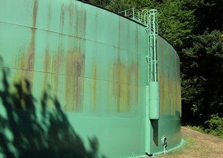 a green water tank in the forest