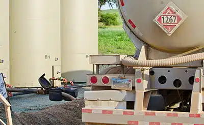 An oil tanker truck pumps oil from containment tanks, in an API 18.2-related scenario